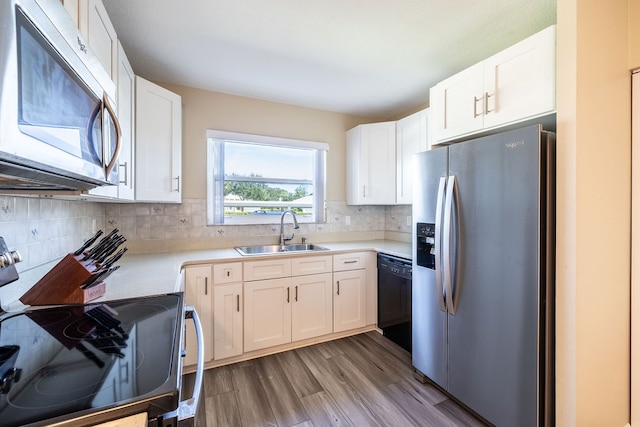 kitchen featuring white cabinets, sink, backsplash, light wood-type flooring, and appliances with stainless steel finishes