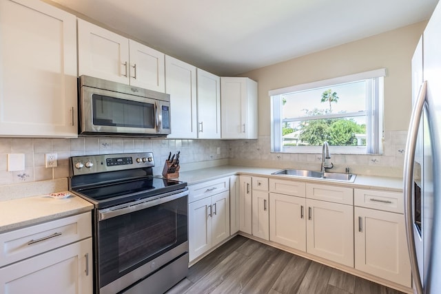 kitchen with stainless steel appliances, dark wood-type flooring, decorative backsplash, sink, and white cabinetry