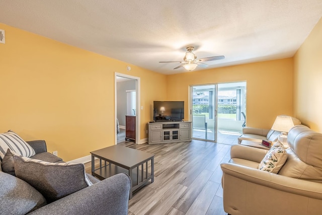 living room with a textured ceiling, light hardwood / wood-style floors, and ceiling fan