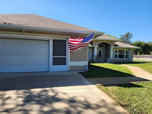 view of front of home with a front yard, stucco siding, concrete driveway, and a shingled roof