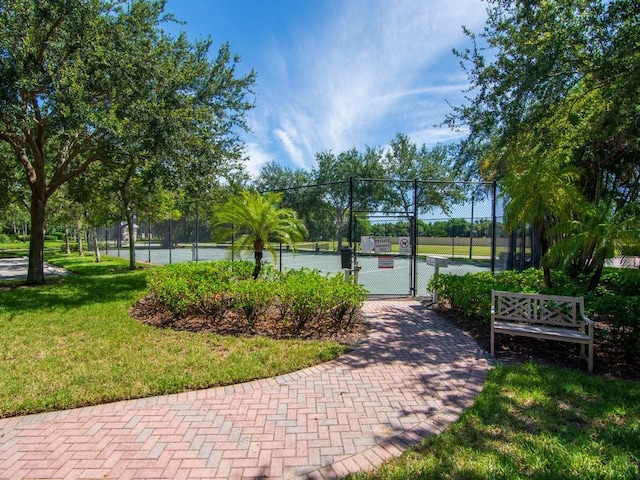 view of property's community with tennis court and a lawn