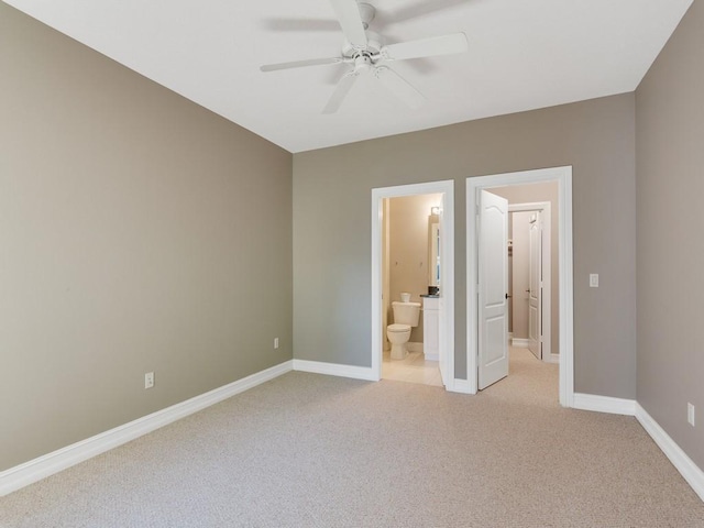 unfurnished bedroom featuring ceiling fan, light colored carpet, and ensuite bath