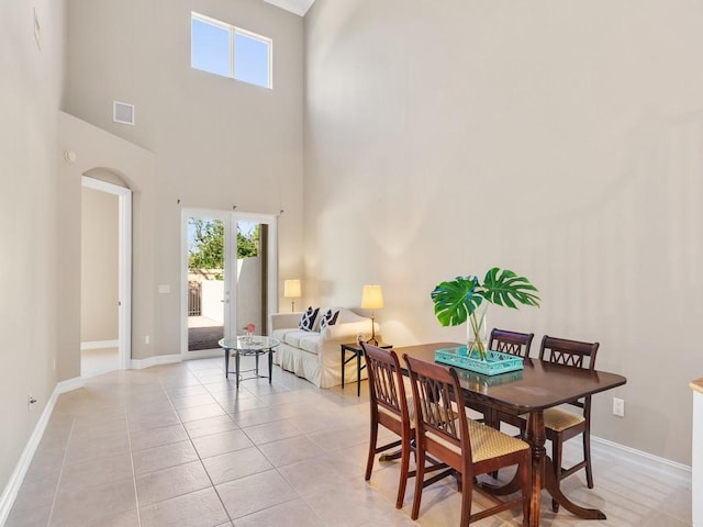 dining area with a towering ceiling and light tile patterned floors