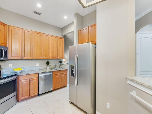 kitchen featuring stainless steel appliances, light stone countertops, sink, and light tile patterned floors