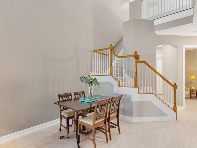 dining space with a high ceiling, crown molding, and light tile patterned floors