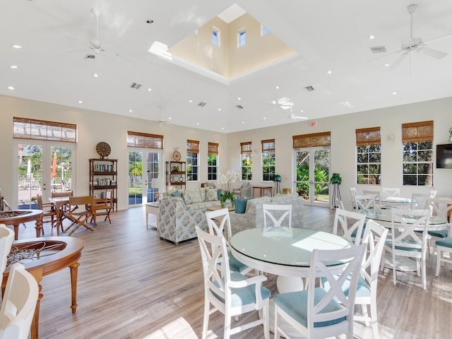 dining space with french doors, ceiling fan, light hardwood / wood-style floors, and a towering ceiling