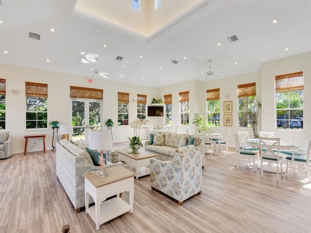 living room with a high ceiling, a wealth of natural light, and light hardwood / wood-style flooring