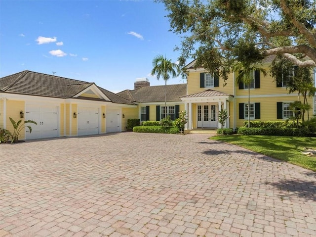505 Live Oak Rd, Vero Beach, FL 32963 - view of front of property with an attached garage, decorative driveway, a chimney, and french doors