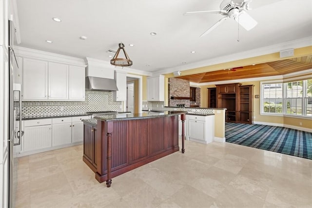 505 Live Oak Rd, Vero Beach, FL 32963 - kitchen with wall chimney range hood, dark countertops, crown molding, open floor plan, and decorative backsplash