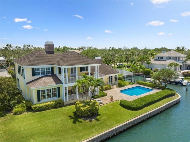 505 Live Oak Rd, Vero Beach, FL 32963 - back of property with a balcony, a chimney, an outdoor pool, a yard, and a metal roof