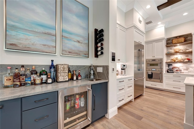 kitchen with stainless steel appliances, white cabinetry, wine cooler, and beam ceiling