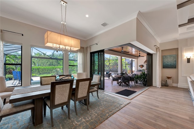 dining space featuring light wood-type flooring, a notable chandelier, and crown molding