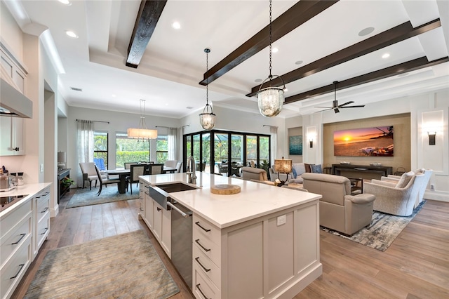 kitchen with light hardwood / wood-style floors, dishwasher, an island with sink, white cabinetry, and decorative light fixtures