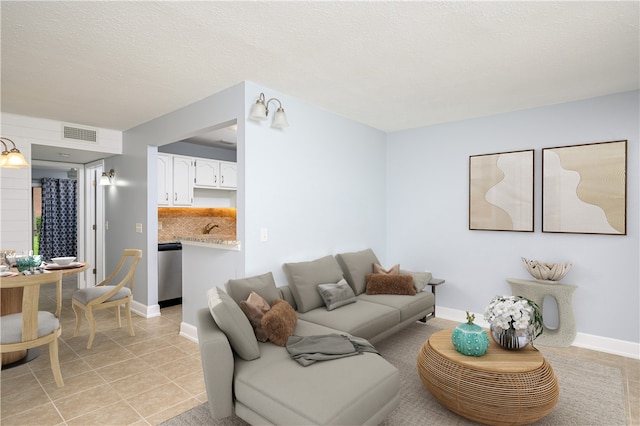 living room with a textured ceiling, sink, and light tile patterned flooring