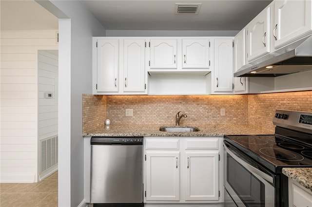 kitchen with light stone counters, stainless steel appliances, white cabinetry, light tile patterned floors, and sink