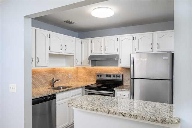 kitchen featuring sink, light stone counters, appliances with stainless steel finishes, tasteful backsplash, and white cabinets