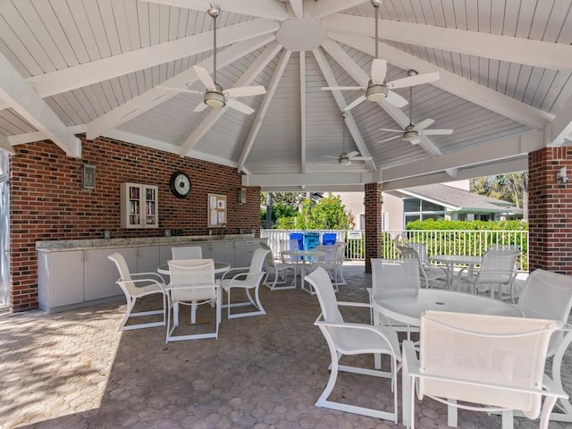 view of patio featuring a sink, fence, a gazebo, outdoor dining area, and ceiling fan