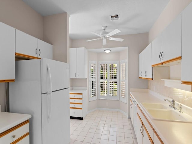 kitchen featuring light countertops, visible vents, freestanding refrigerator, and a sink