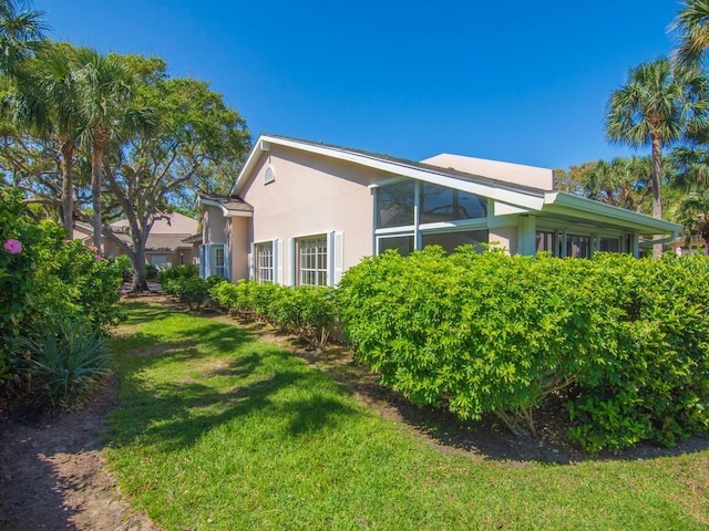 view of side of home with a lawn and stucco siding