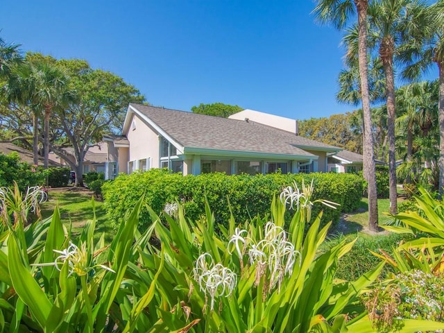 view of side of property with stucco siding and roof with shingles