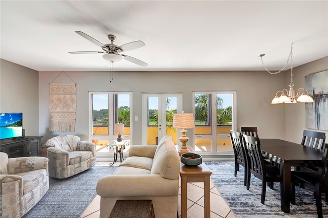 living room with ceiling fan with notable chandelier, plenty of natural light, and light tile patterned floors