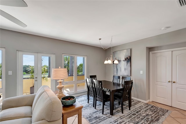 dining area with french doors, light tile patterned floors, and ceiling fan with notable chandelier