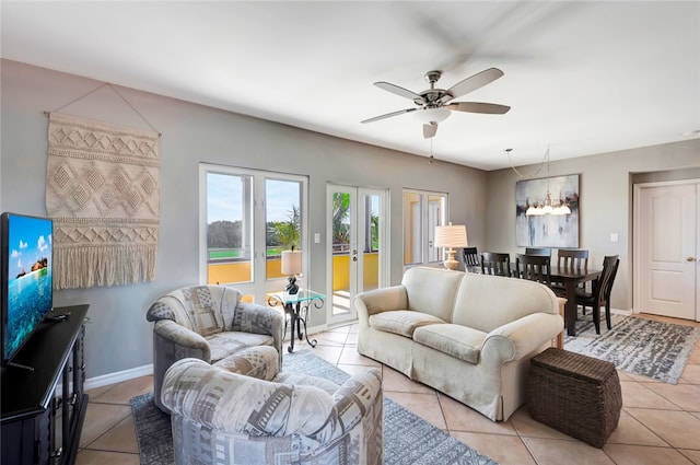 living room featuring ceiling fan with notable chandelier, light tile patterned floors, and french doors