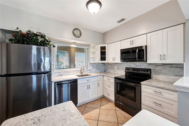 kitchen featuring stainless steel appliances, light stone counters, sink, backsplash, and white cabinetry