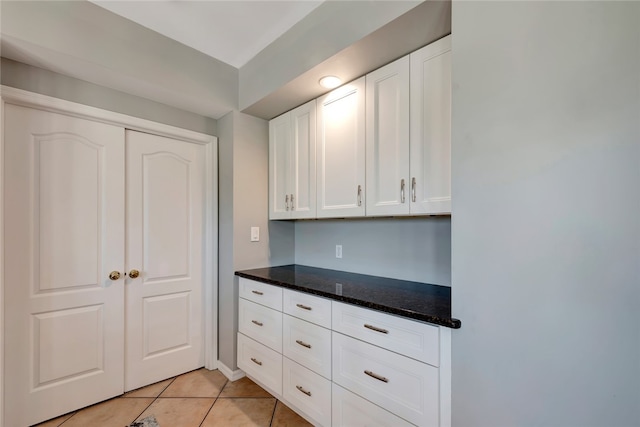 kitchen featuring dark stone counters, light tile patterned floors, and white cabinets