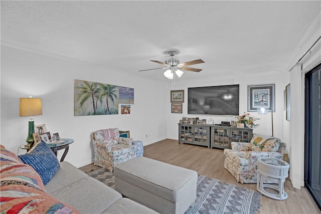 living room featuring a textured ceiling, hardwood / wood-style flooring, ceiling fan, and crown molding