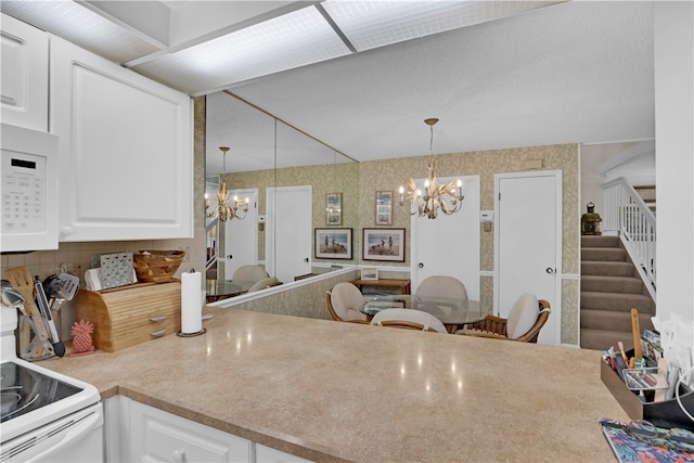 kitchen featuring white appliances, decorative light fixtures, a notable chandelier, and white cabinets