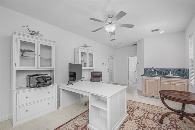 office area featuring visible vents, a sink, baseboards, and a ceiling fan