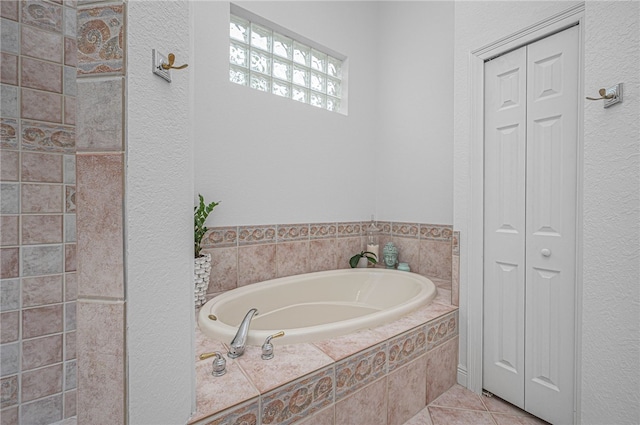 bathroom featuring tile patterned flooring, a closet, a textured wall, and a garden tub