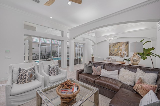 living area featuring decorative columns, crown molding, arched walkways, ceiling fan with notable chandelier, and recessed lighting