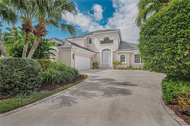 view of front of house featuring an attached garage, stucco siding, concrete driveway, and a tile roof