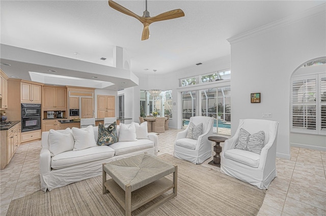 living room with crown molding, ceiling fan with notable chandelier, and light tile patterned flooring