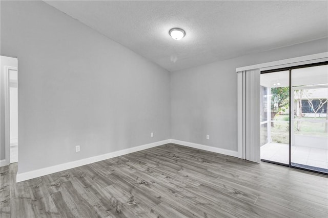 empty room with light hardwood / wood-style floors and a textured ceiling