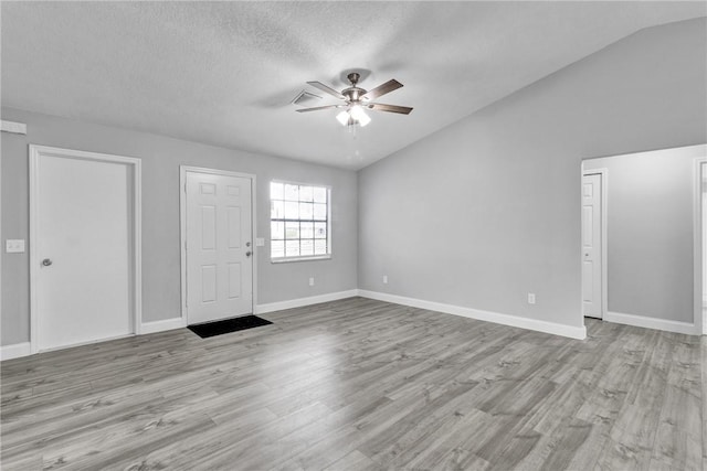 unfurnished room featuring ceiling fan, light hardwood / wood-style floors, lofted ceiling, and a textured ceiling