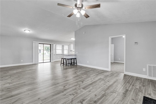 unfurnished living room featuring a fireplace, light wood-type flooring, ceiling fan, and lofted ceiling