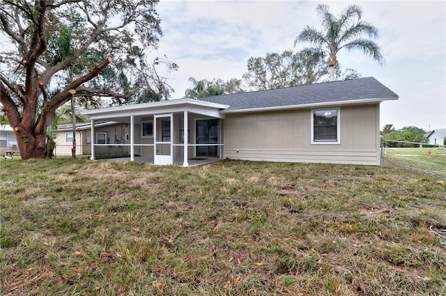 back of property with a sunroom and a yard