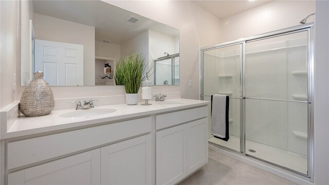 bathroom with a sink, visible vents, a shower stall, and double vanity