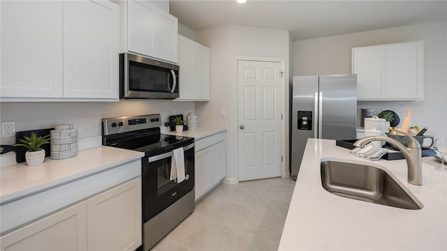 kitchen with a sink, light countertops, appliances with stainless steel finishes, and white cabinetry