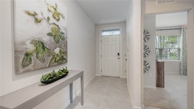 foyer featuring light carpet, light tile patterned floors, visible vents, and baseboards