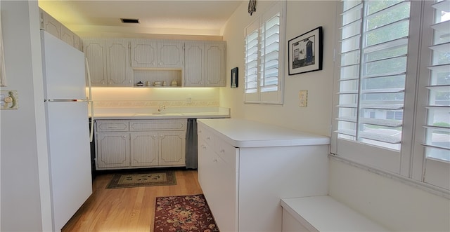 kitchen with white cabinetry, light wood-type flooring, white refrigerator, a textured ceiling, and sink