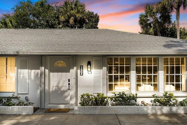646 Honeysuckle Ln, Vero Beach, FL 32963 - exterior entry at dusk featuring roof with shingles