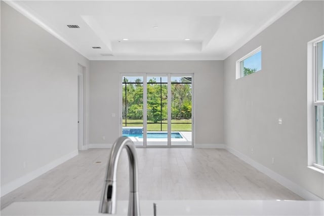 interior space featuring a tray ceiling and light hardwood / wood-style flooring