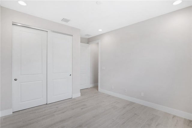 unfurnished bedroom with light hardwood / wood-style flooring and a closet