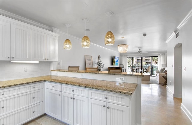 kitchen featuring white cabinetry, kitchen peninsula, backsplash, decorative light fixtures, and crown molding