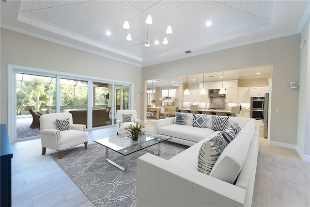 living area with a raised ceiling, an inviting chandelier, a high ceiling, and a healthy amount of sunlight