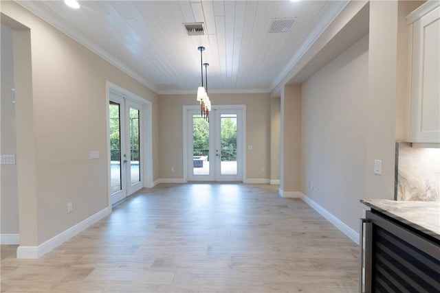 unfurnished dining area with beverage cooler, visible vents, crown molding, and french doors